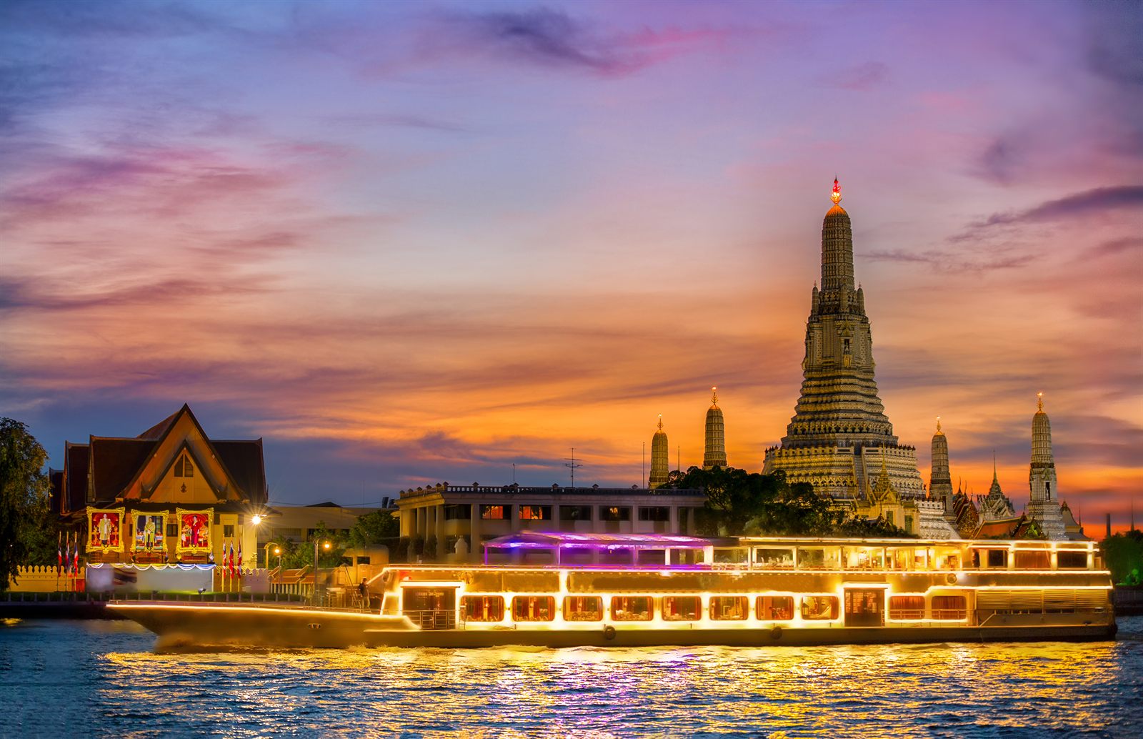 Illuminated river boat passing Wat Arun on the Chao Phraya in Bangkok at dusk